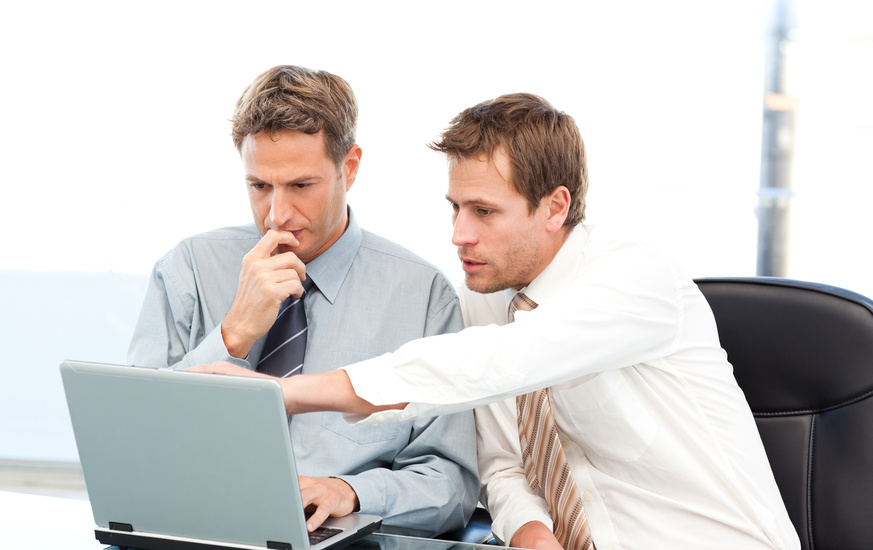 Two handsome businessmen working together on a project sitting a